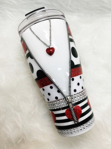 a white and black cup with red hearts on it sitting on top of a fur rug