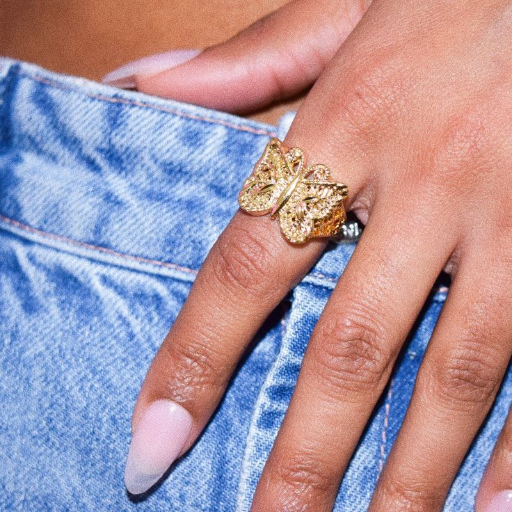 a close up of a person's hand with a ring on her finger and jeans