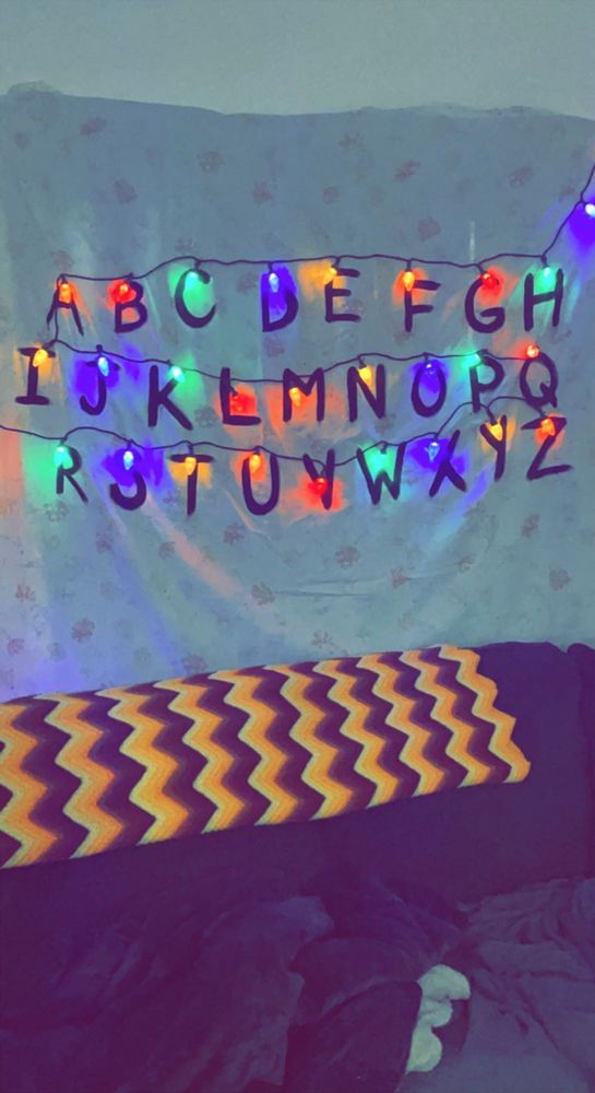 a bed covered in blankets and lights with the letters above it that spell out alphabets