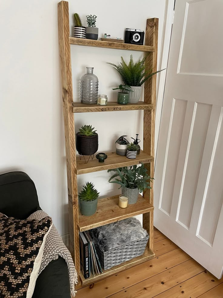 a wooden shelf with plants on it in a living room next to a black chair