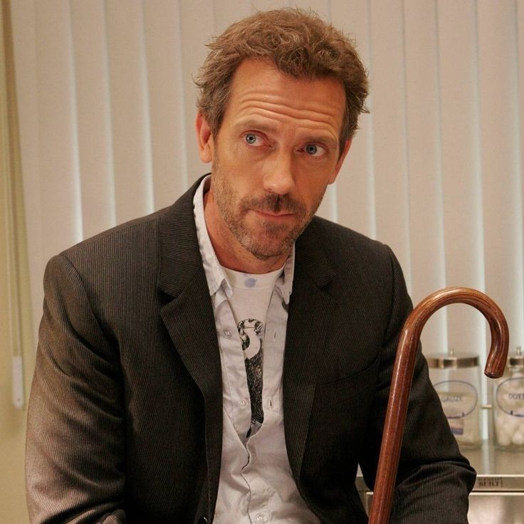 a man in a suit and tie sitting on a chair with an umbrella over his shoulder