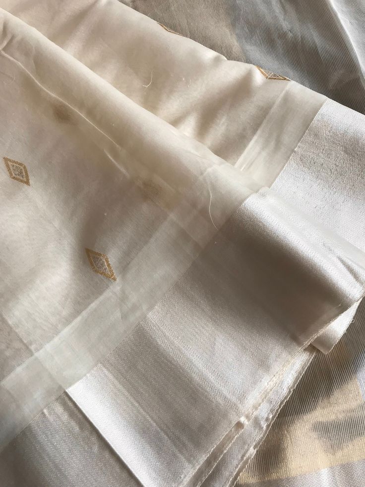 This is a beautiful handloom off-white maheswari silk by cotton saree with beautiful diamond shaped sona roopa booties, silk borders and tisuue pallu with gold and silver stripe zari in pallu. Saree is finished with tassels. Sarees comes with a plain unstitched blouse piece with borders similar to the saree. Falls and pico are already done. Colours may vary slightly depending upon the lighting and individual device settings. Dry clean only All sales are final. Handloom products may have some irregularities unlike power loom products. Unstitched White Saree With Pallu Detail, White Semi-stitched Saree With Pallu, Unstitched Cream Saree, Semi-stitched Cream Dola Silk Saree, Semi-stitched White Tissue Silk Saree, Traditional Silk Saree, South Indian Sarees, Sari Blouse, Silk Cotton Sarees