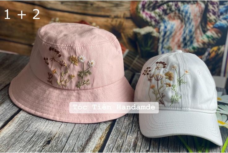 two hats sitting on top of a wooden table next to each other and one has flowers embroidered on it