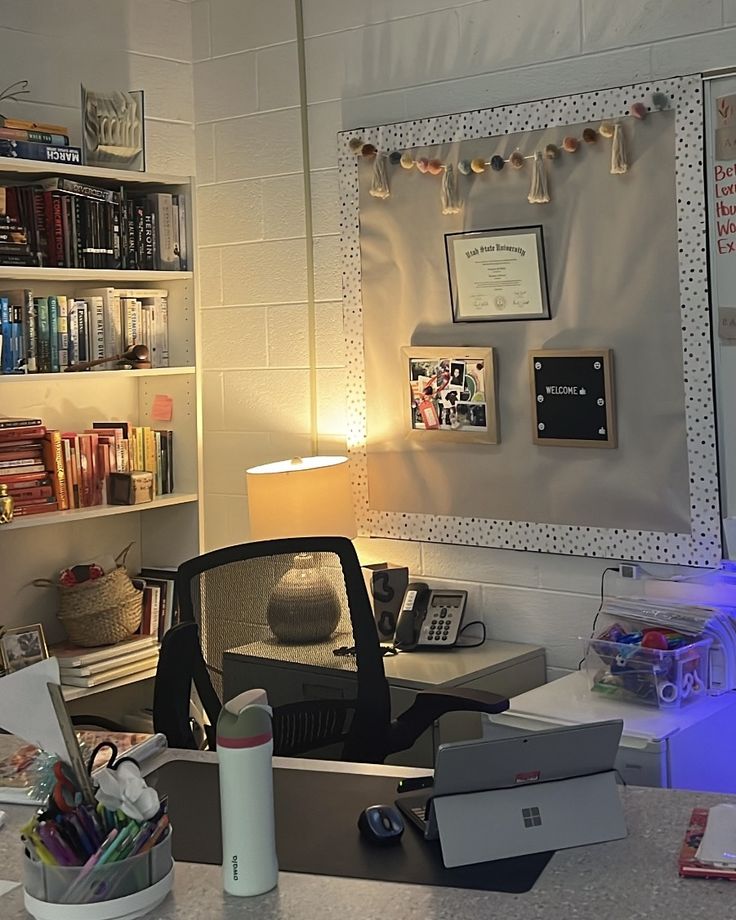 a desk with a laptop computer sitting on top of it next to a book shelf