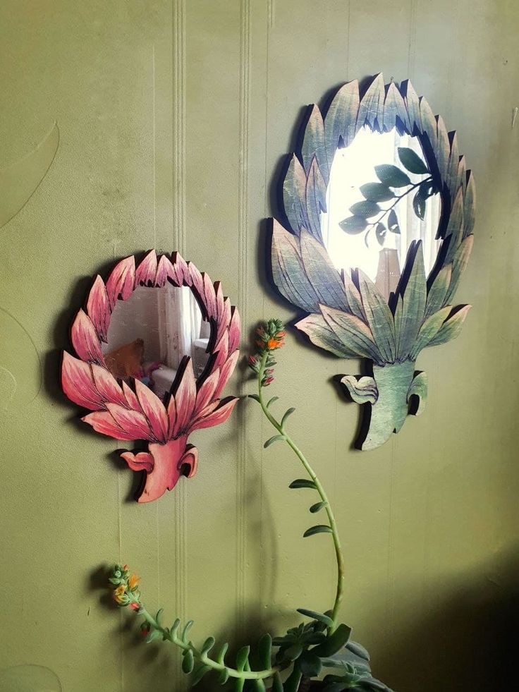 there are two mirrors on the wall and one is painted pink with flowers in it