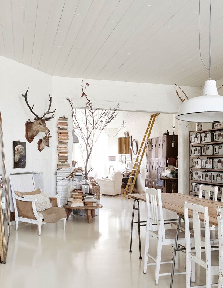 a living room filled with white furniture and lots of deer head mounted on the wall