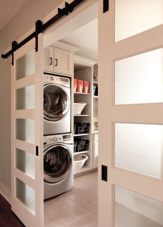 an open door leading to a washer and dryer in a room with white cabinets