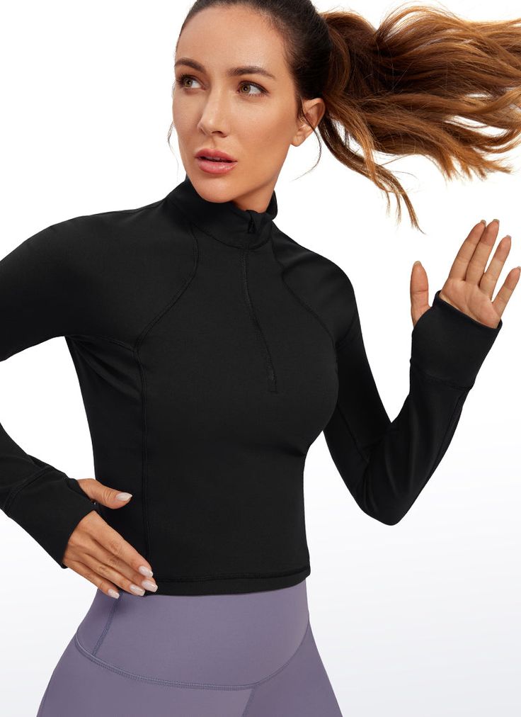 a woman with her hair in the air and wearing a black top that has a high neck