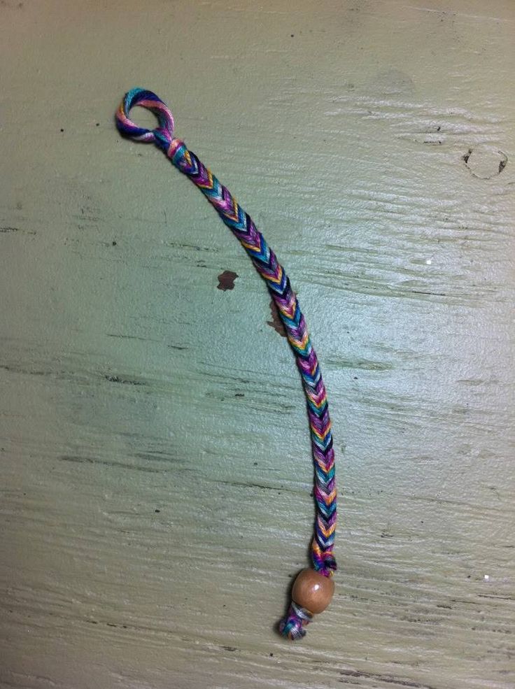 a colorful rope with beads hanging from it's end on a wooden surface,