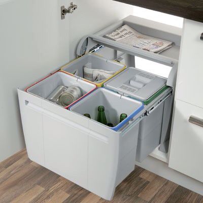 two bins are open in the corner of a kitchen with white cabinets and wood flooring