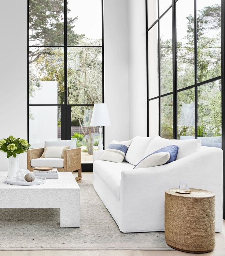 a living room with white furniture and large windows