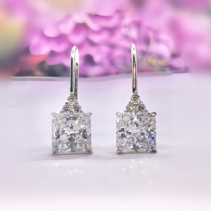 These Stunning Moissanite Diamond Dangle Drop Earrings, are a great gift, and are sure to compliment any outfit you choose. Our Jewelry is all handmade to assure durability and quality. Length: 2.4 cm Main Stone Size: 8 mm X 8 mm (2 Carat / each) Main Stone Colour: Clear White Main Stone Shape: Princess Cut Metal: Real Solid 925 Sterling Silver Hallmark: 925 Plating: Rhodium Plated Stones Setting: Prong Stones: High Quality Lab Moissanite Diamond Finish: High Polished Guaranteed High Quality Comes in a wrapped gift box Princess Dangle Drop Earrings 2 Carat Square Cut Lab Moissanite Diamond Dangle Drop 925 Sterling Silver Bridal Wedding Earrings Gift Boxed Classic Diamond Drop Earrings With Ear Wire, Fine Jewelry Drop Earrings With Lever Back, Dazzling Diamond White Dangle Earrings, Elegant Diamond Cut Earrings Gift, Silver Moissanite Drop Earrings, Gift Diamond White Hoop Earrings With Prong Setting, Diamond Dangle Earrings With Prong Setting, Classic Diamond Cut Drop Earrings, Diamond White Hoop Earrings With Prong Setting As Gift