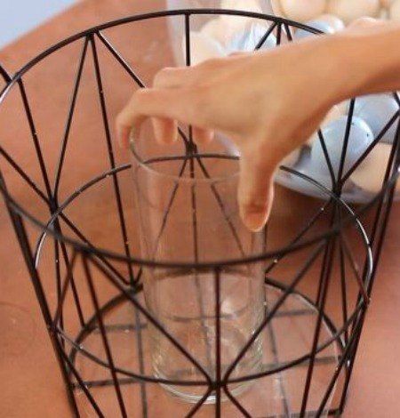 a person's hand reaching into a wire basket on top of a wooden table