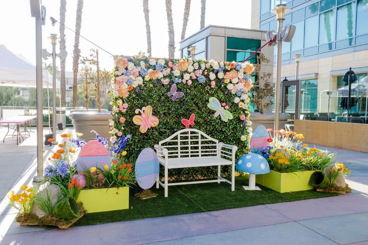 a white bench sitting in front of a green wall with flowers and butterflies on it