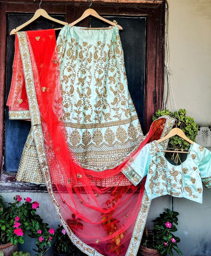 Elegance personified! Our Teal Silk Lehenga Choli, adorned with intricate floral Zardozi, heavy stones, and Kundan work on the lehenga and blouse, exudes opulence. The contrasting Red dupatta, with a soft net Zardozi border, adds a touch of grandeur to this stunning ensemble. Perfect for weddings and special occasions. Size - L  Stitched - Yes fully Stitched  Colors - Teal, Gold, and Red   Neck - Round neck choli with Dori at the back  Country of Manufacture - India  Wash Care - Dry Clean Only Traditional Wear With Floral Embroidery In Brocade For Reception, Brocade Lehenga With Floral Embroidery For Wedding, Wedding Lehenga With Floral Embroidery In Brocade, Traditional Gown With Gold Embroidery, Wedding Silk Thread Embroidered Sets, Multicolor Embroidered Gown With Dupatta For Wedding, Anarkali Style Brocade Lehenga With Floral Embroidery, Traditional Gown With Floral Embroidery For Reception, Wedding Choli With Floral Embroidery In Silk Thread