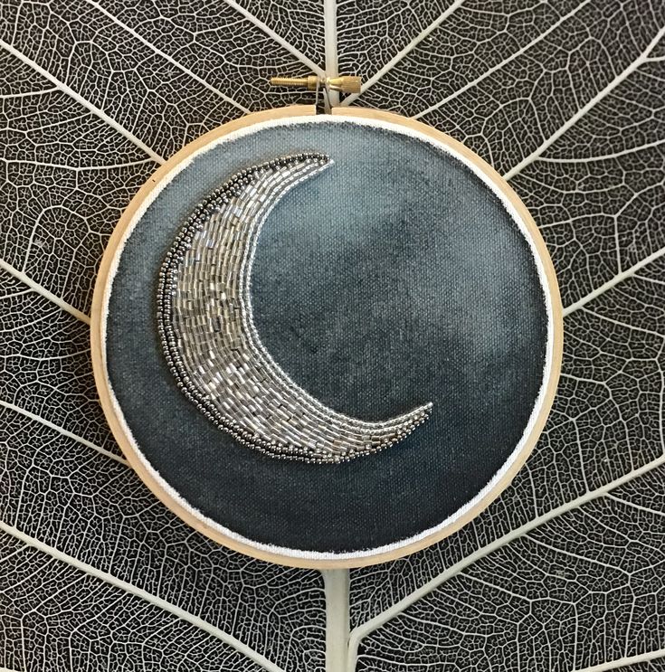 the embroidery pattern is on top of a leaf and it has a crescent in the middle