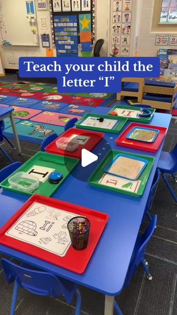 a classroom with blue desks and red trays filled with different colored papers on them