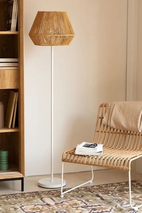 a wicker floor lamp sitting next to a book shelf