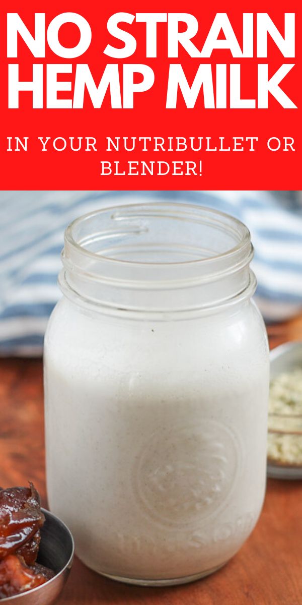 a glass jar filled with milk sitting on top of a wooden table next to a spoon