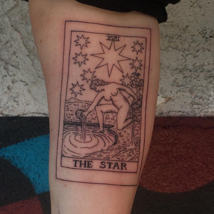 a tarot card tattoo on the leg of a person's leg with stars above it