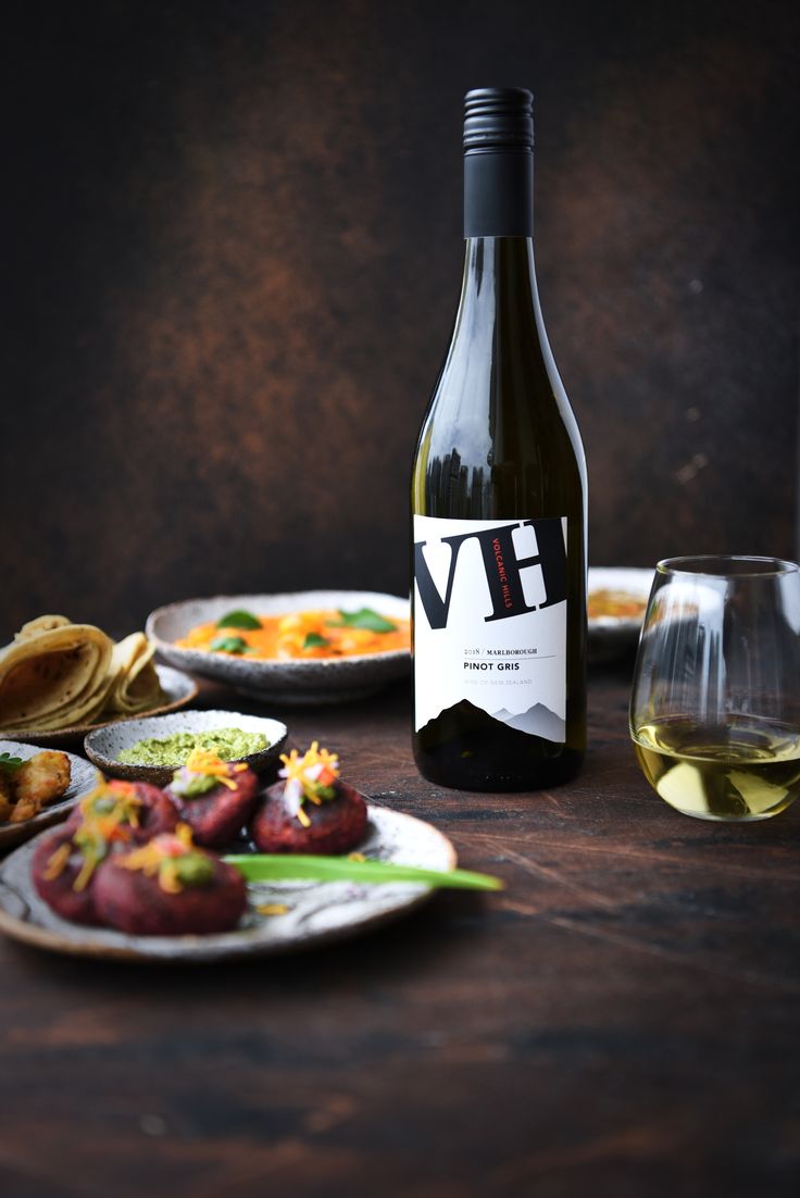 a bottle of wine sitting on top of a wooden table next to plates of food