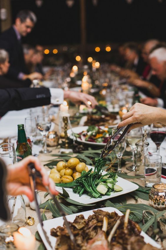 people sitting at a long table with plates of food and wine glasses on the table