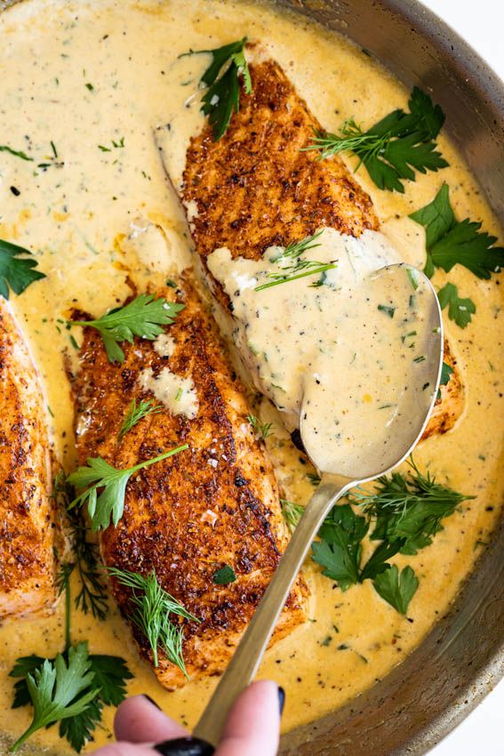 someone is spooning some food out of a skillet with broth and parsley