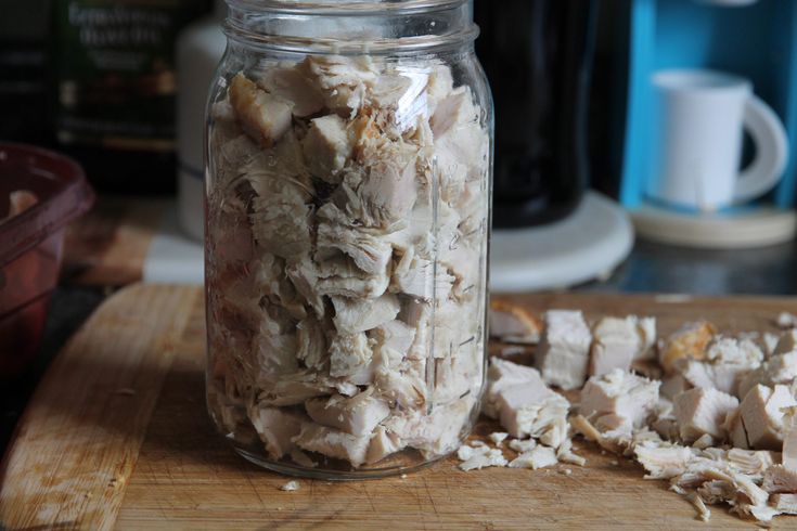 a jar filled with chopped meat sitting on top of a wooden cutting board