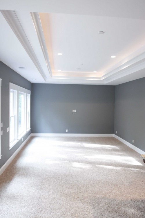 an empty room with gray walls and white trim on the ceiling is pictured in this image