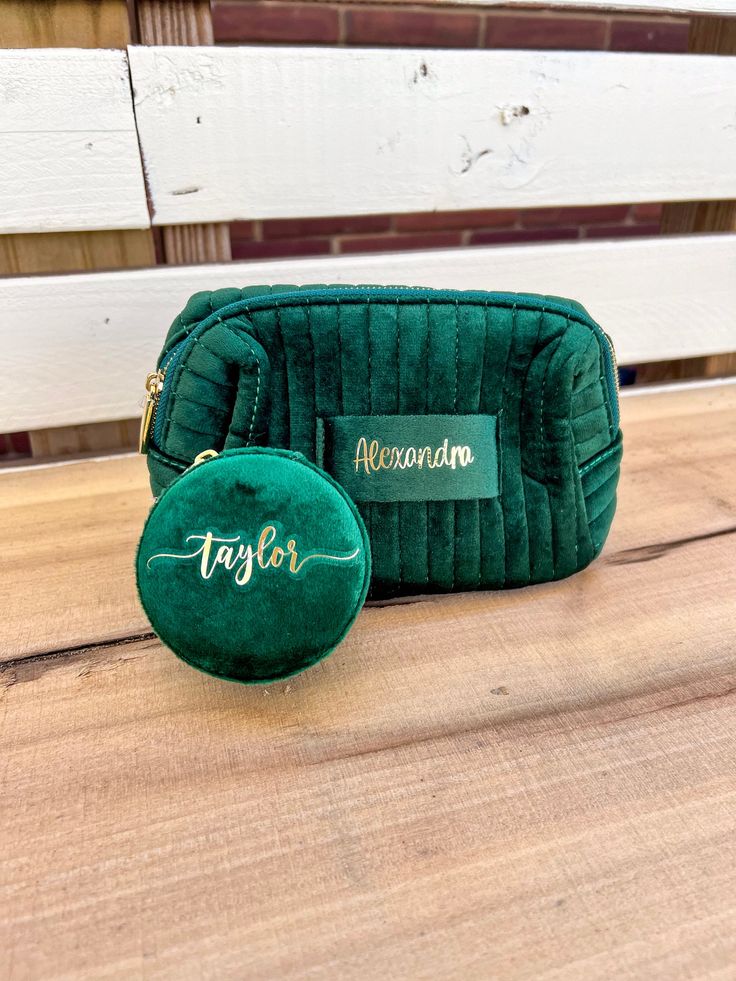 a green purse sitting on top of a wooden table next to a small round bag