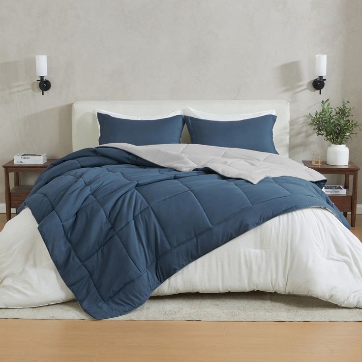 a bed with blue and white comforters in a room next to a wooden floor