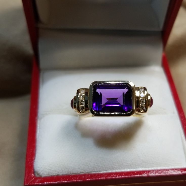 Lovely And Unusual 14kt Yellow Gold Amethyst Ring. High Quality Amethyst Bezel Set Sideways In Between Two Rows Of Channel Set Round Diamonds With A Cabochon Ruby On Either Side. In Excellent Condition, Is About A Size 7 Now, But Sizable. All Stones Are Genuine And 4 Grams In Weight. Elegant Purple Birthstone Ring With Gemstone Accents, Classic Amethyst Rings With Gemstone Accents, Formal Purple Sapphire Ring With Gemstone Accents, Elegant Purple Sapphire Ring With Gemstone Accents, Elegant Purple Gemstone Birthstone Ring, Elegant Purple Birthstone Ring With Accent Stones, Classic Amethyst Jewelry With Center Stone, Purple Ring With Gemstone Accents For Formal Occasions, Formal Amethyst Birthstone Ring With Gemstone Accents