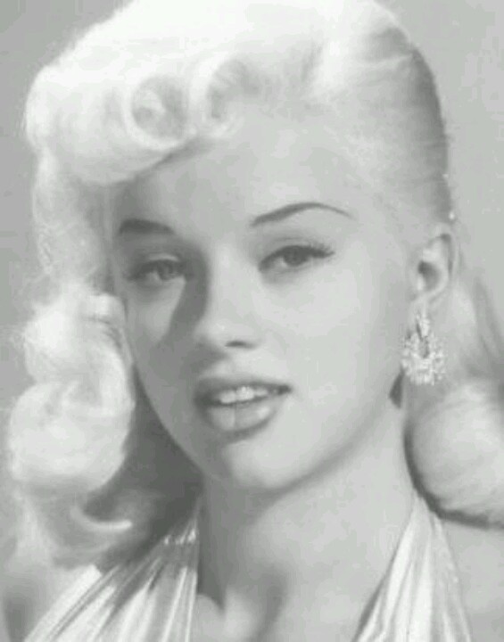 a black and white photo of a woman with blonde hair wearing pearls on her necklace