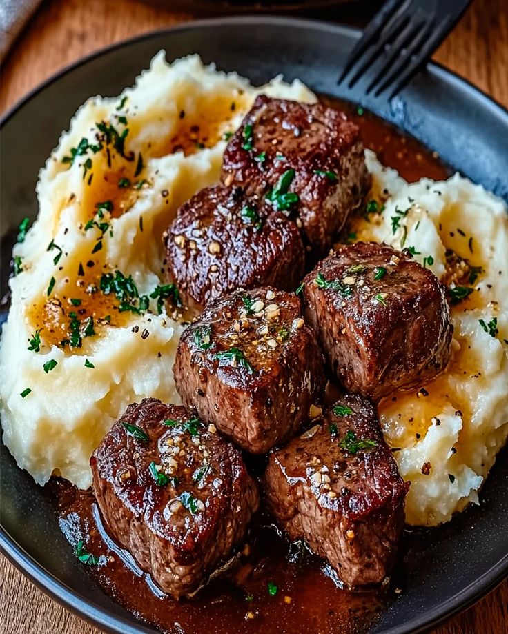 some meat and mashed potatoes on a black plate