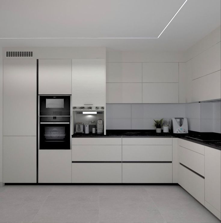 a modern kitchen with white cabinets and black counter tops, along with an oven in the center