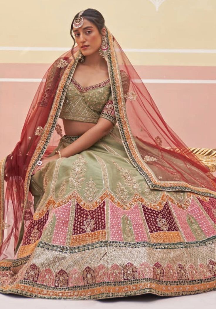 Introducing the Mehendi Green Silk Bridal Lehenga, a masterpiece of elegance and tradition. This stunning bridal lehenga features intricate zardozi embroidery with silken threads, dabka, cutdana, and sequins underlayed with multi colored velvet appliques. The green raw silk blouse perfectly complements the lehenga, while the double dupatta in matching green and contrasting crimson adds a touch of opulence. Make your wedding day truly unforgettable with this exquisite bridal wedding dress. Composition : Lehenga and Blouse - Raw Silk, Dupatta - Soft Net Care: Dry Clean Only and Vacuum Storage This product can be customized for sleeves, length of blouse and neckline Delivery : 2-4 weeks as the product is hand crafted. Check Size Guide or choose MySize for free customisation (All Sizes above X Embroidered Semi-stitched Lehenga For Traditional Ceremonies, Semi-stitched Meenakari Lehenga For Wedding, Semi-stitched Anarkali Lehenga With Meenakari, Bollywood Style Embroidered Choli For Traditional Ceremonies, Wedding Semi-stitched Jamawar Choli, Semi-stitched Jamawar Choli For Wedding, Jamawar Lehenga For Wedding With Traditional Drape, Wedding Lehenga With Jamawar Fabric And Dupatta, Wedding Lehenga With Intricate Embroidery In Jamawar