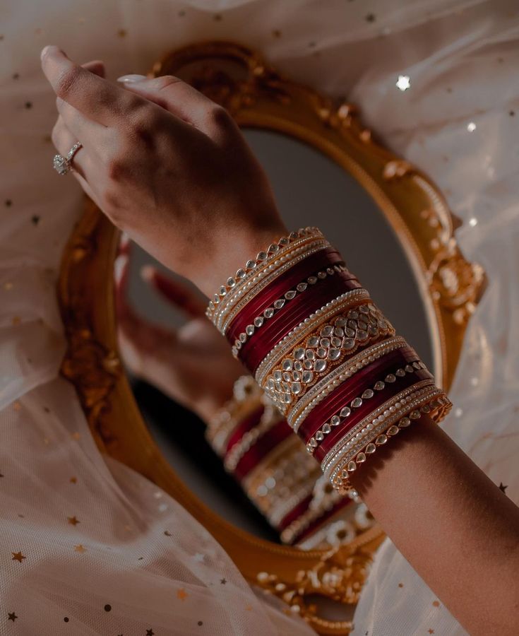 a woman's arm with bracelets on it and a mirror in the background