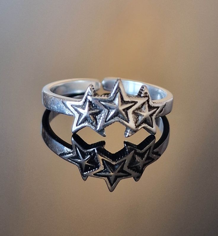 This sterling silver 925 row of 3 stars is very comfortable to wear, these boho rings are minimalist and both eye catching, they come gift wrapped and make a wonderful gift for her, either as a Mother's Day gift, birthday gift, anniversary gift, stocking filler or treat yourself. Stars are symbolic of divinity with a belief being that the countless stars we see in the distance are fallen angels cast out from heaven. For this reason, stars can often be seen referenced as divine light. In general, Star Themed Christmas Gifts, Star Promise Rings, Adjustable Star Shaped Stackable Promise Rings, Adjustable Star-shaped Midi Rings As Gift, Adjustable Star Midi Rings For Promise, Adjustable Star Midi Rings For Promises, Adjustable Star-shaped Midi Rings, Cool Silver Rings, Star Gifts