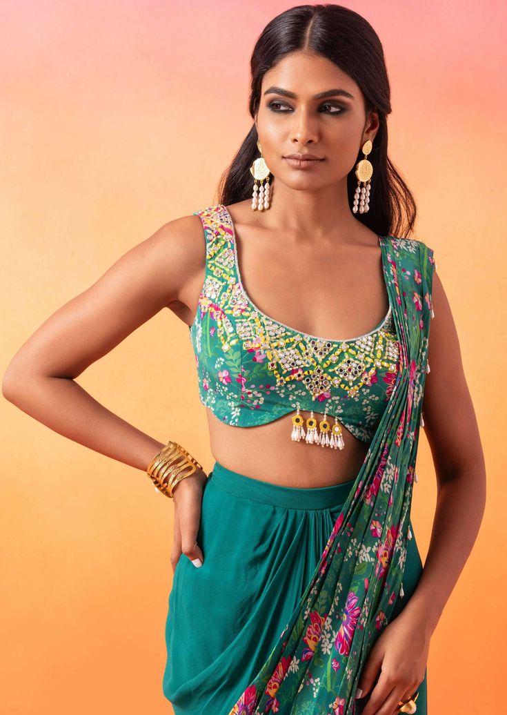 Emerald green embellished printed choli paired with a draped skirt and pre-stitched floral printed pallu finished with tassels. Summer Choli With Resham Embroidery In Traditional Drape, Festive Georgette Choli With Side Open, Festive Unstitched Side Open Choli, Green Traditional Drape Choli For Summer, Green Summer Choli With Traditional Drape, Anarkali Style Sleeveless Pre-draped Saree, Festive Anarkali Style Pre-draped Sleeveless Saree, Sleeveless Choli With Dupatta For Diwali, Festive Unstitched Side-open Choli