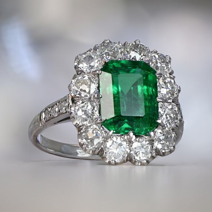 A rare and beautiful cluster ring that centers a natural emerald cut emerald weighing approximately 2.18-carat. Old European cut diamonds are arranged in a cluster around the central stone weighing approximately 1.50 carats in a low profile platinum ring. ✦ GEMSTONE SPECIFICATIONS: Center Gemstone: Emerald Center Gemstone Weight: Approx 2.18 Carats ✦ ENGAGEMENT RING SPECIFICATIONS: Total Diamond Weight: Approx 1.50 Carats Ring Material: Platinum ✦ WHAT COMES IN YOUR SHIPMENT: - Your Ring - Quali Emerald Ring With Diamonds, Biedermeier Furniture, Estate Diamond Jewelry, Mercedes Maybach, Yellow Gold Engagement, Yellow Gold Engagement Rings, European Cut Diamonds, Emerald Jewelry, Platinum Ring