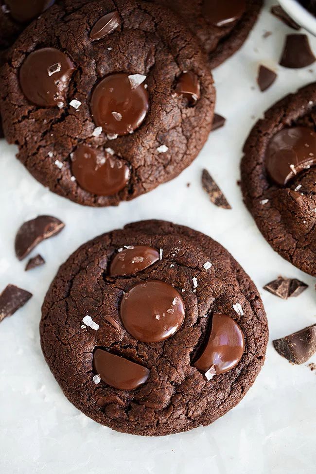 three chocolate cookies with sea salt on top and one cookie has been cut in half