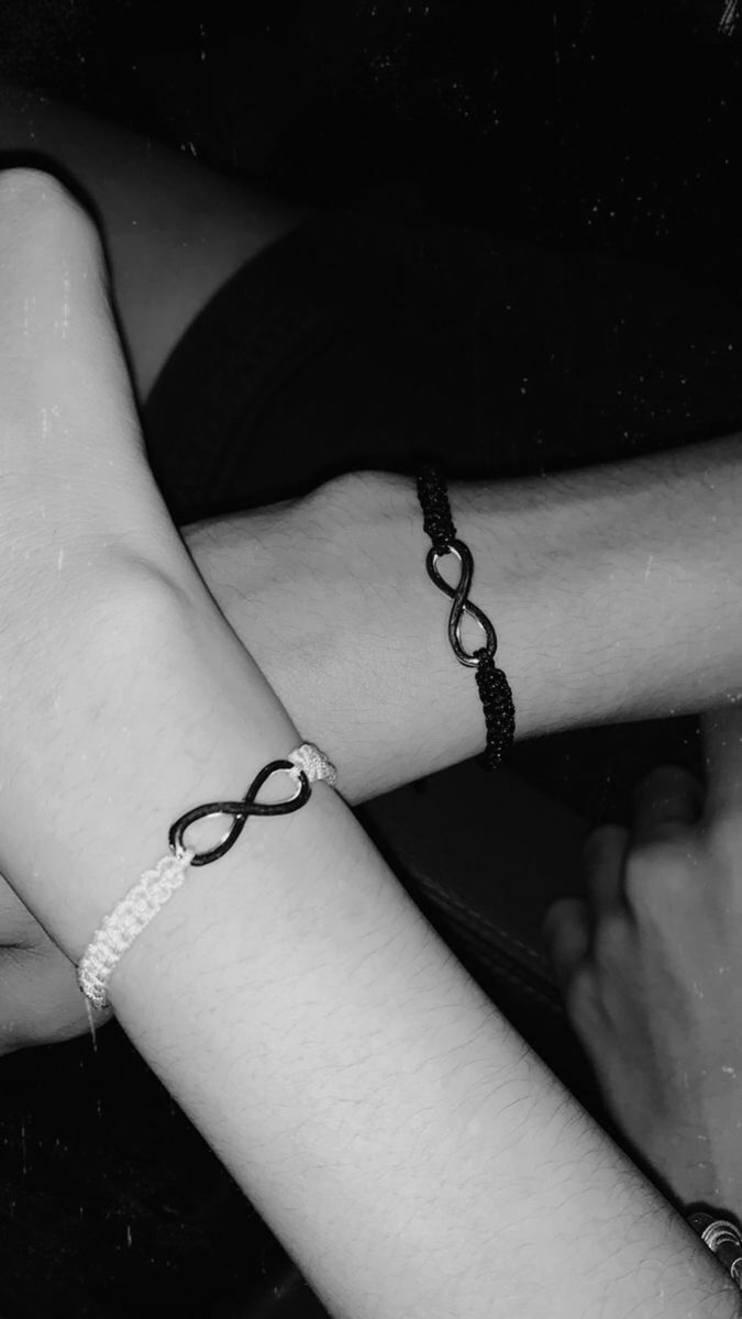 black and white photo of two people with bracelets on their arms, one holding the other's arm