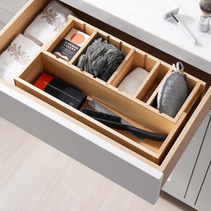 an open drawer with various items in it on a countertop next to a sink