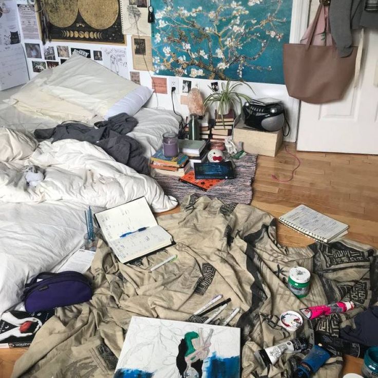 an unmade bed in a messy room with pictures on the wall and other items scattered around it