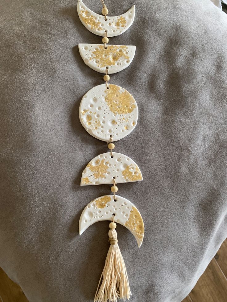 three moon and tassels hanging from the back of a pillow on a chair