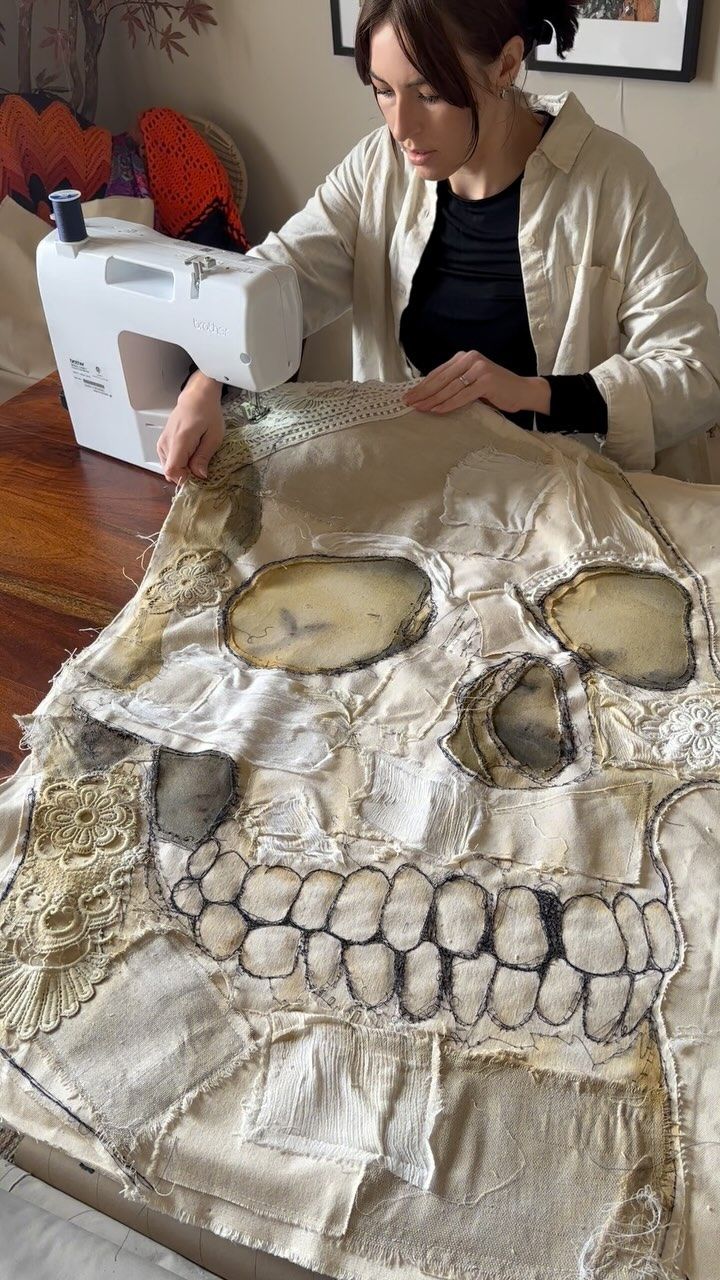 a woman sitting at a table working on a piece of fabric with a sewing machine