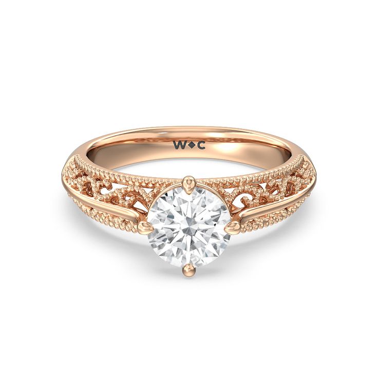 a yellow gold engagement ring with a round diamond in the center and filigrees around the band