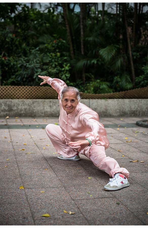 an older woman in pink is stretching on the ground