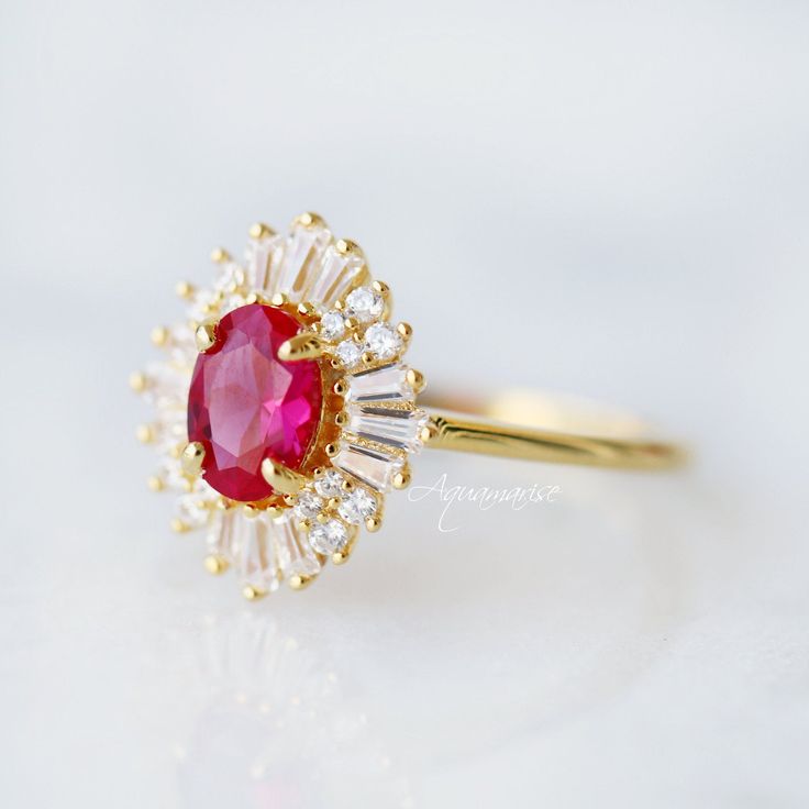 Beautiful Vintage Inspired Ruby Ring ►Base Metal: Sterling Silver (925) ►Plating: 14K Gold ►Accented With Simulated Diamonds ►Please be aware that plated jewelry can wear off over time, if this is a concern we would suggest going with the sterling silver or solid gold jewelry option. ►Style: Art-Deco Main Stone: Ruby Color: Red Gemstone Creation: 100% Genuine Lab-Grown Ruby Stone Shape: Oval Cut Gem size: 7.0 x 5.0 mm Carat Weight: 0.76 ct. (Approx.) ►Handling time: 1-2 business days ►Free domes Classic Halo Cluster Ring For Proposal, Timeless Ruby Rings For Wedding, Classic Ruby Ring With Halo Design, Classic 14k Gold Ruby Ring With Halo Design, Heirloom Cluster Ring With Halo For Anniversary, Heirloom Halo Cluster Ring For Anniversary, Heirloom Style Anniversary Cluster Ring With Halo, Heirloom Anniversary Cluster Ring With Halo, Fine Jewelry 14k Stamped Halo Wedding Ring