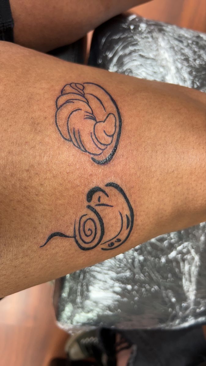 a close up of a person's arm with tattoos on it and an image of a snail